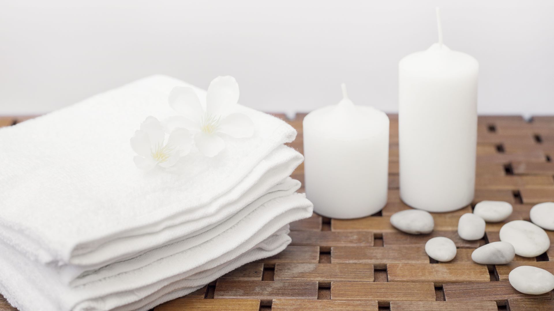 close up white towel flowers candles pebbles wooden table