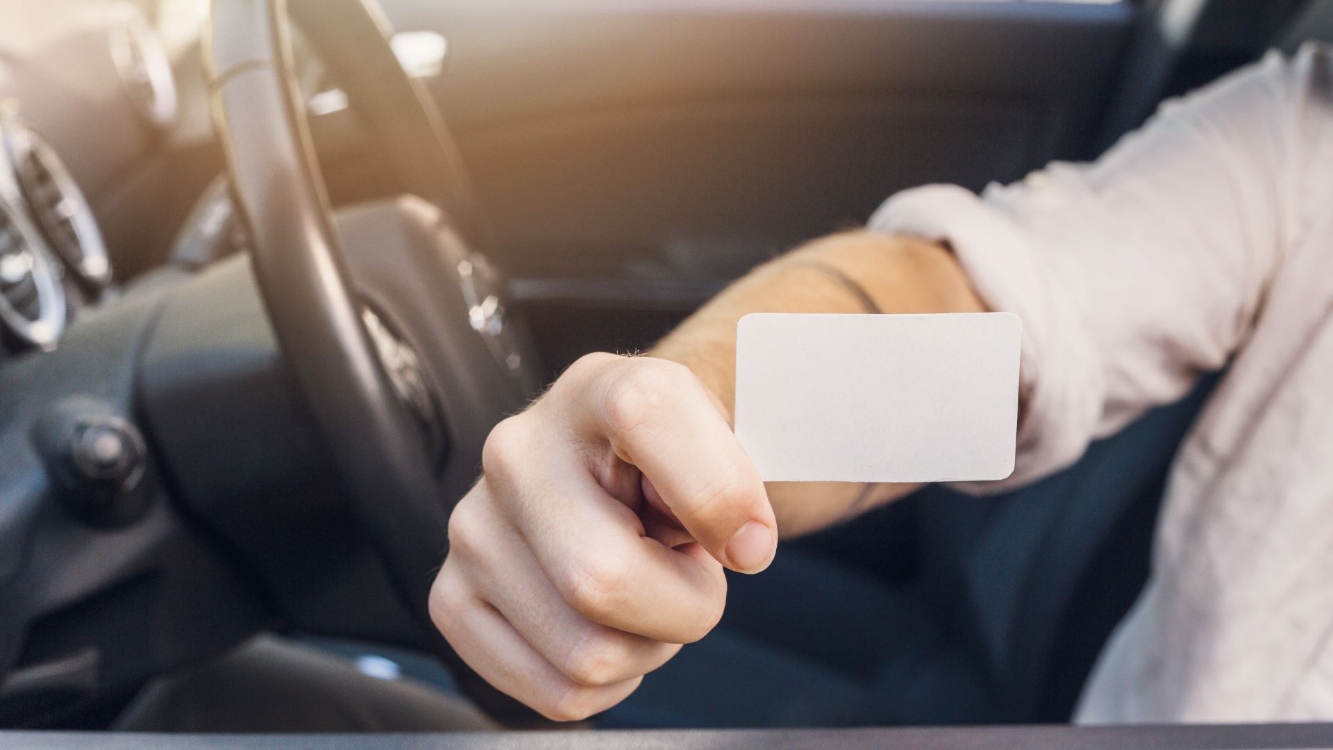 man showing business card car